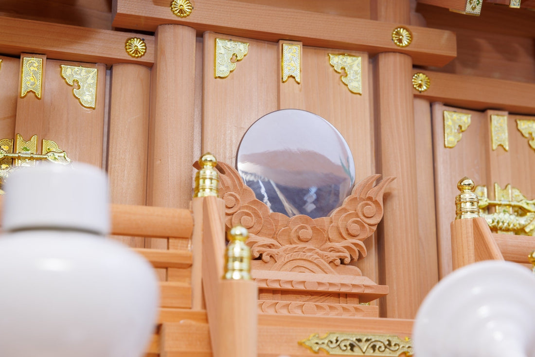 宮形の正面に神鏡を据えた木製の神棚。手前に白い瓶子が並ぶ