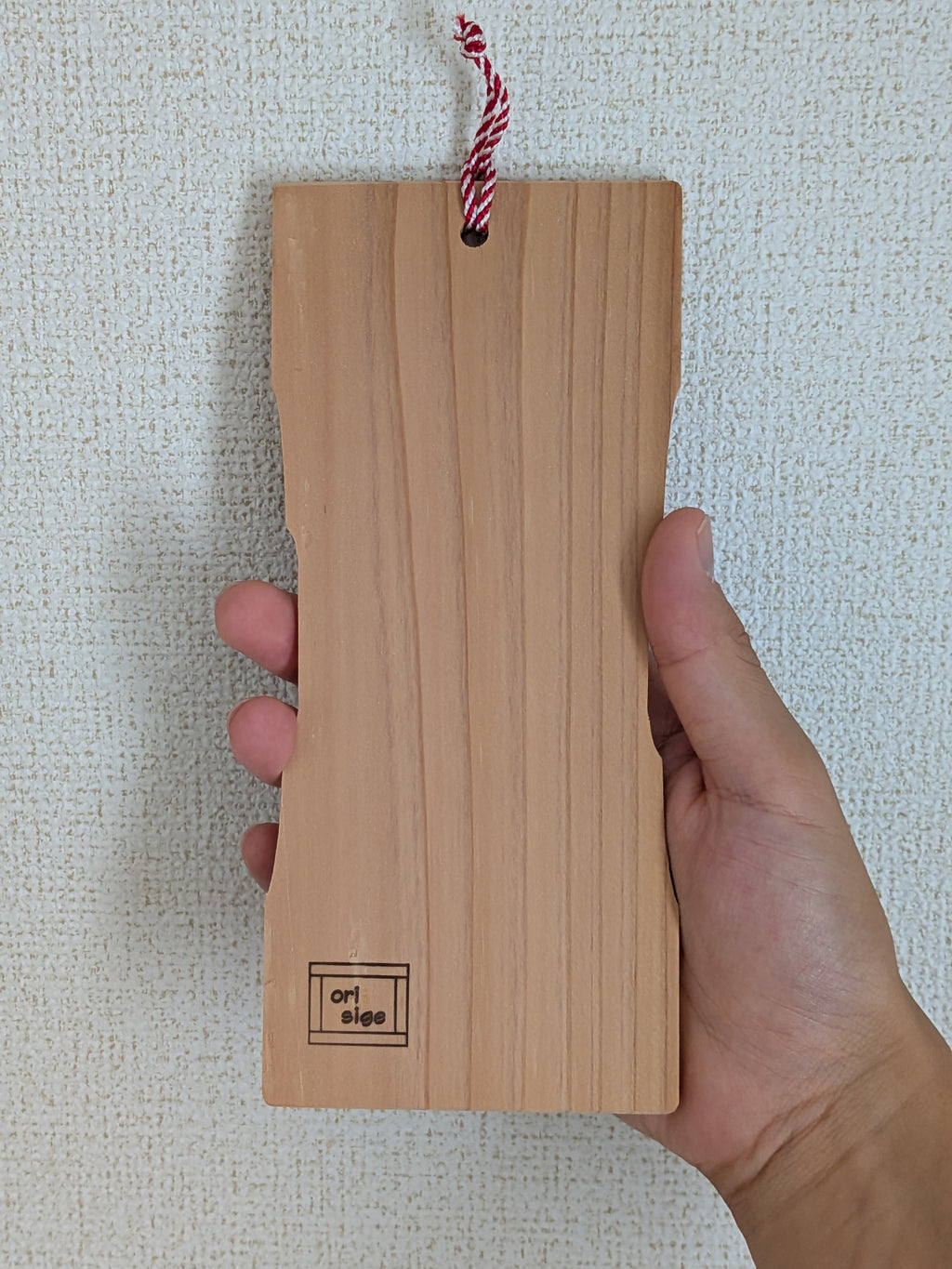 inori 壁掛けver.の裏側を手に持ったところ。手のひらに収まる大きさで、左下にorisigeの焼印がある