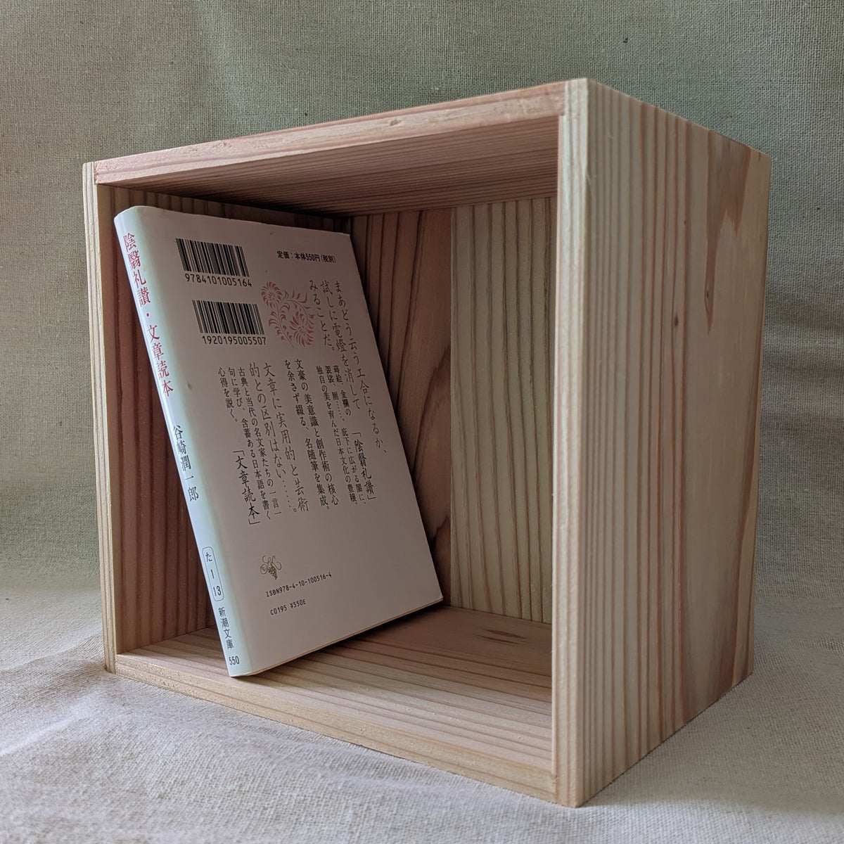 無垢杉の箱に文庫本を一冊立てかけた状態。手前の木口に薄板を貼り重ねた層が見える